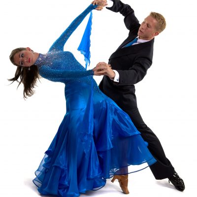 Young ballroom dancers in formal costumes posing against a solid background in a studio